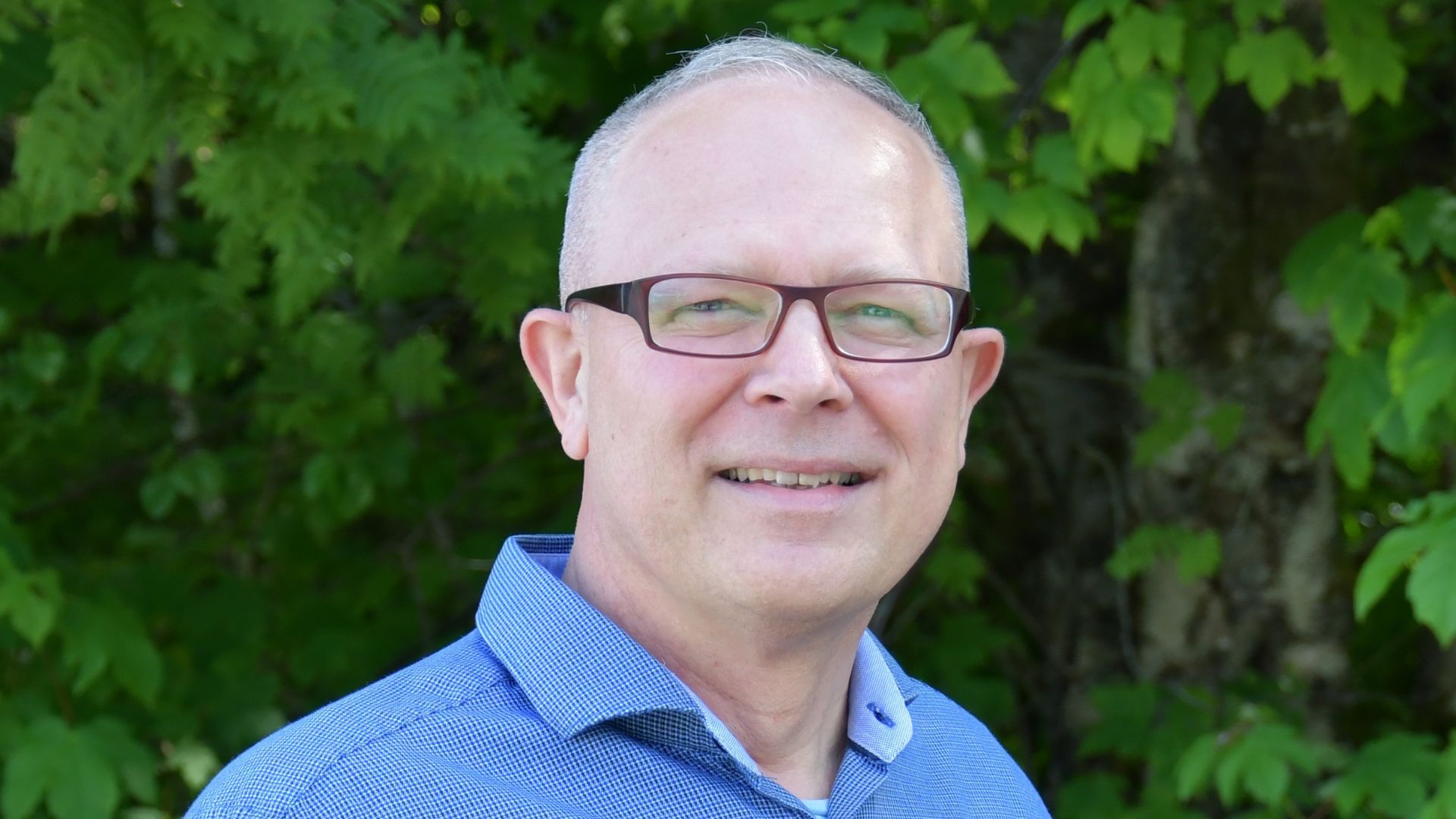 Harald Lillebø, daglig leder i Energiråd, står utendørs foran grønne busker.