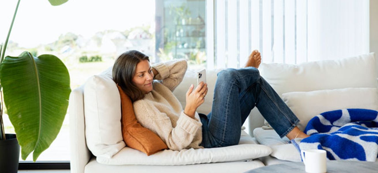 Dame i sofaen som sitter på mobilen.