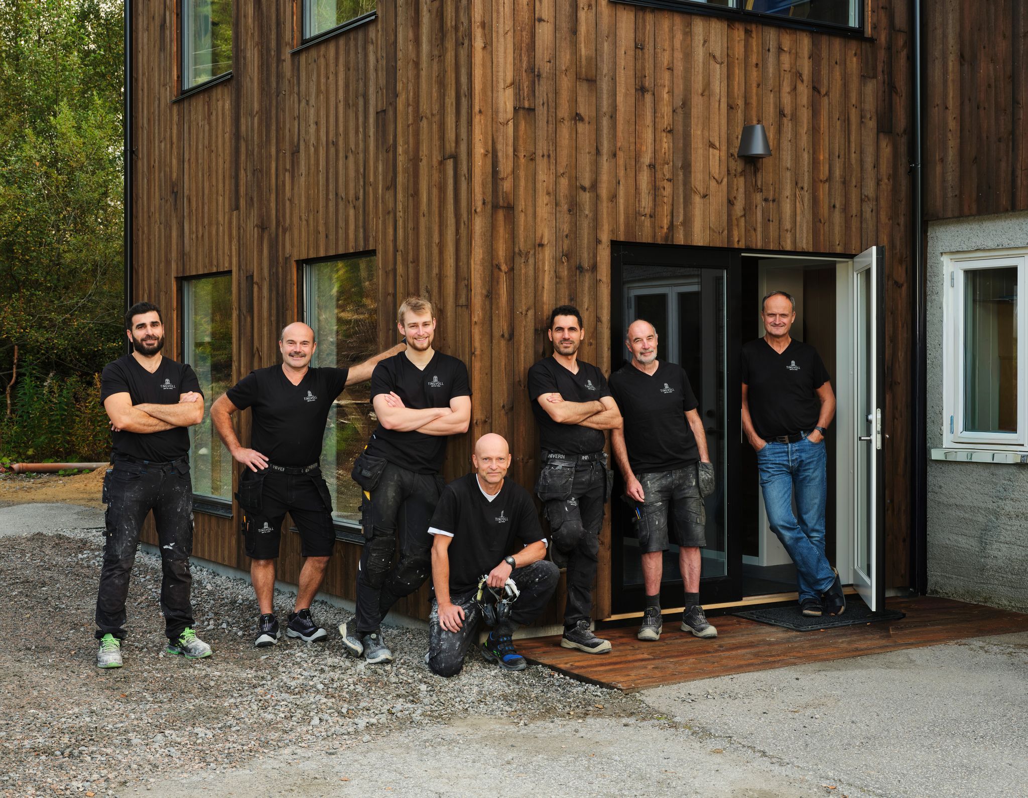 Ansatte i Tingvoll Dør og Vindu utenfor et bygg med trekledning, produsent av skreddersydde dører og vinduer på Nordmøre