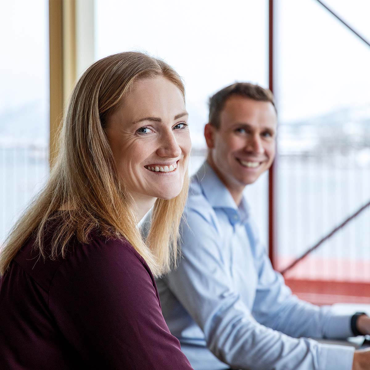 Ung kvinne som er ut av vinduet med kaffi i hånden, moderne leilighet i by. 