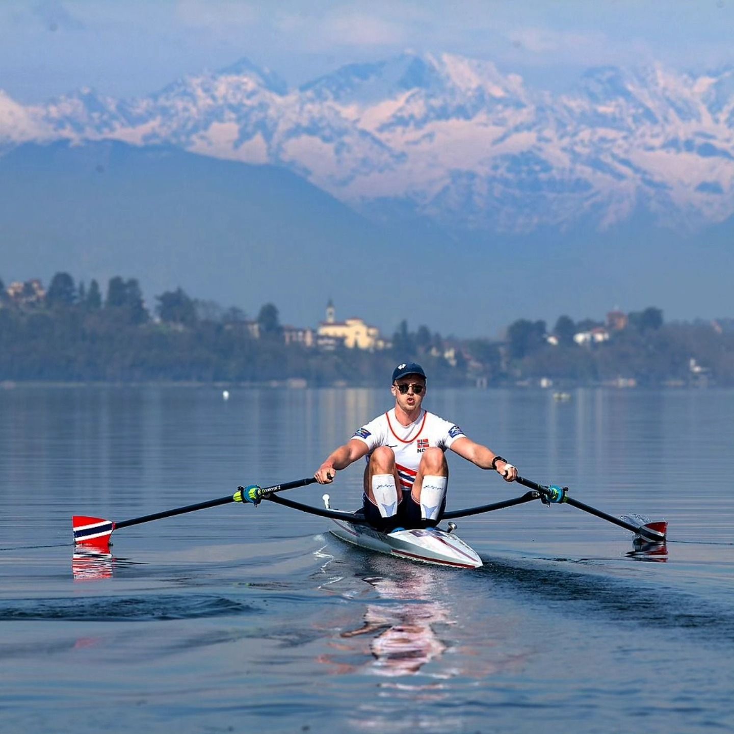 Martin Helseth som ror med fjell og bebyggelse i bakgrunn