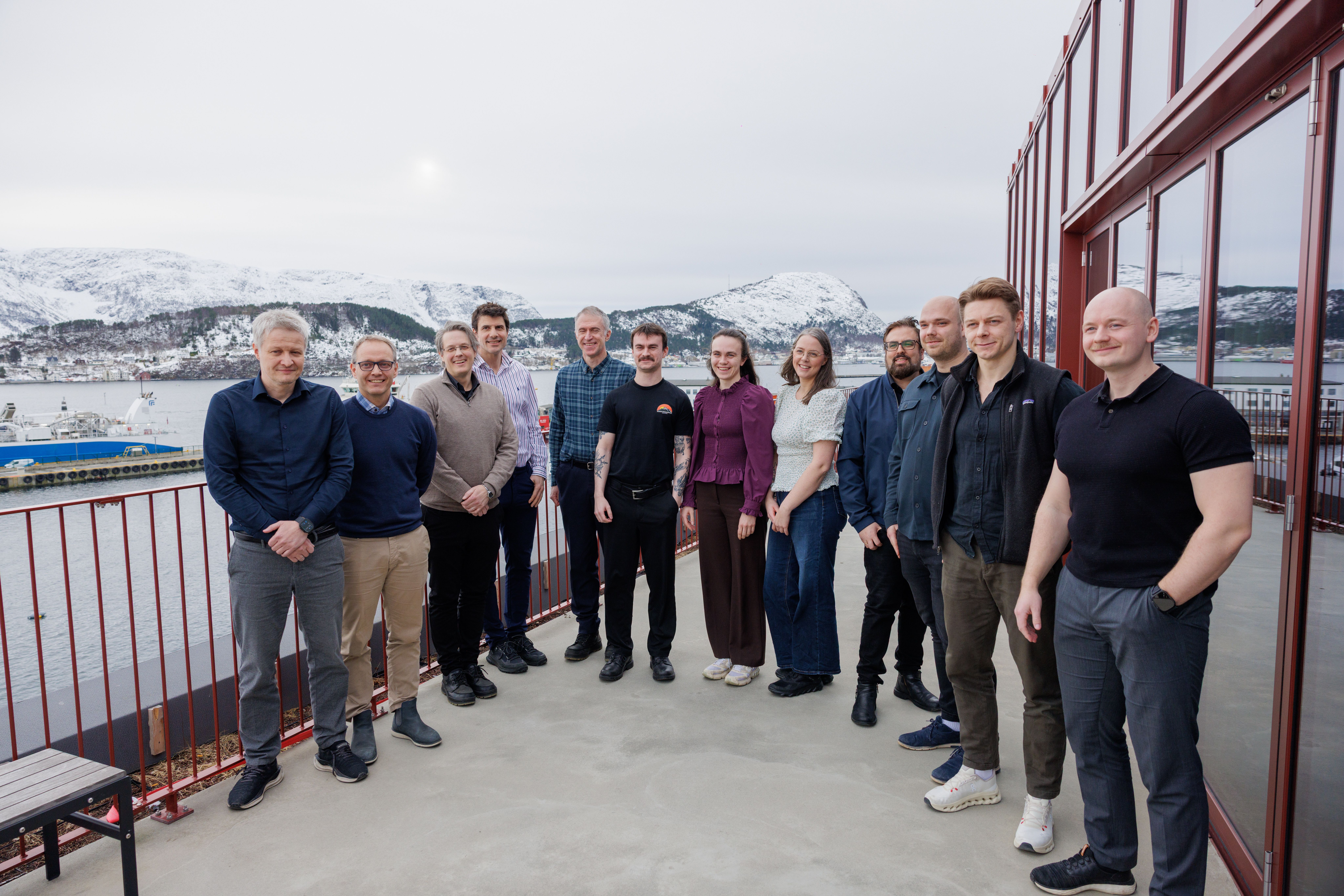 Bilde av finalistene i Næringsteft. Kvinner og menn oppstilt på veranda med bylandskap i bakgrunn. 